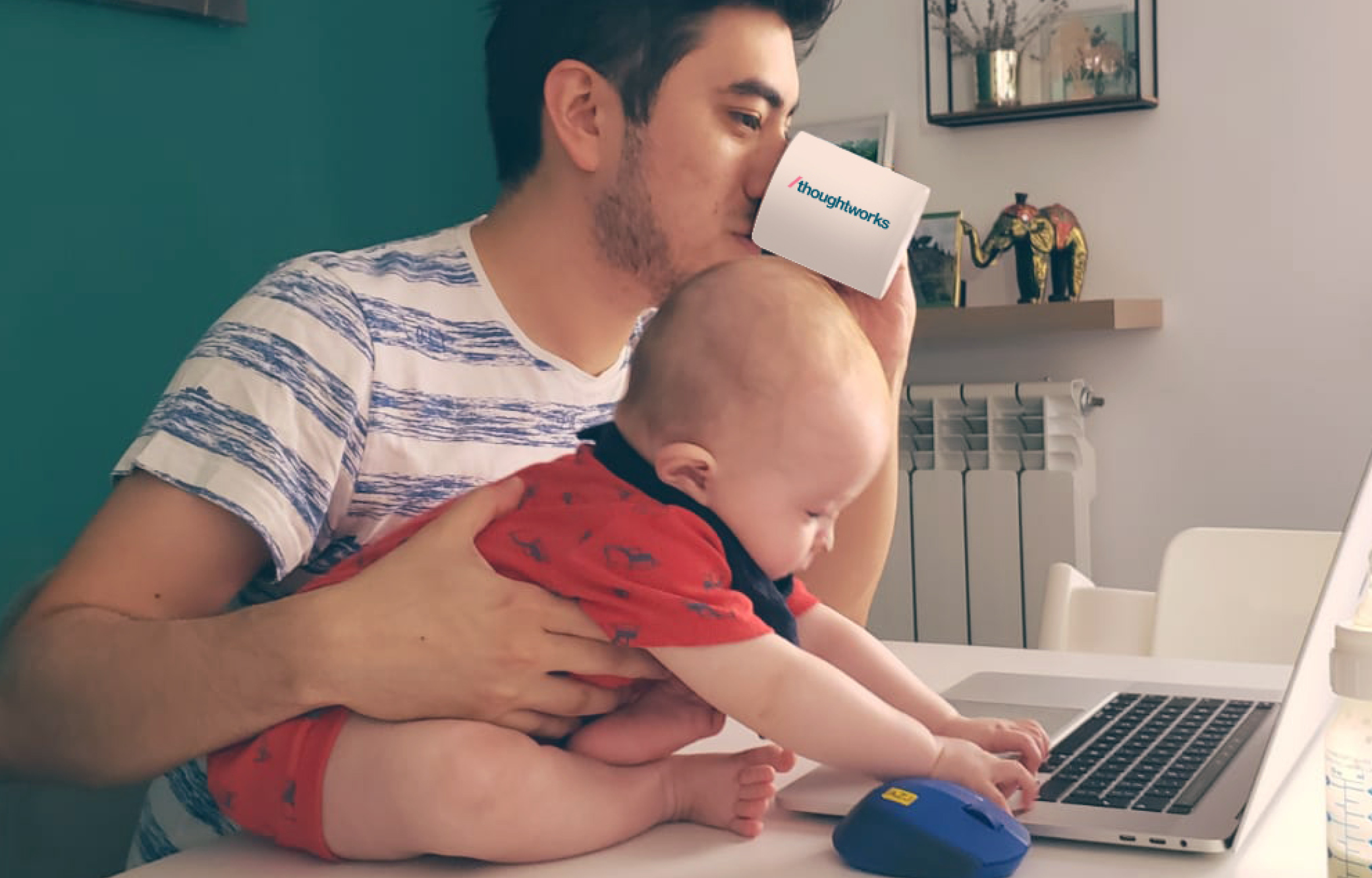 Thoughtworker with their child holding a cup and looking at the computer.