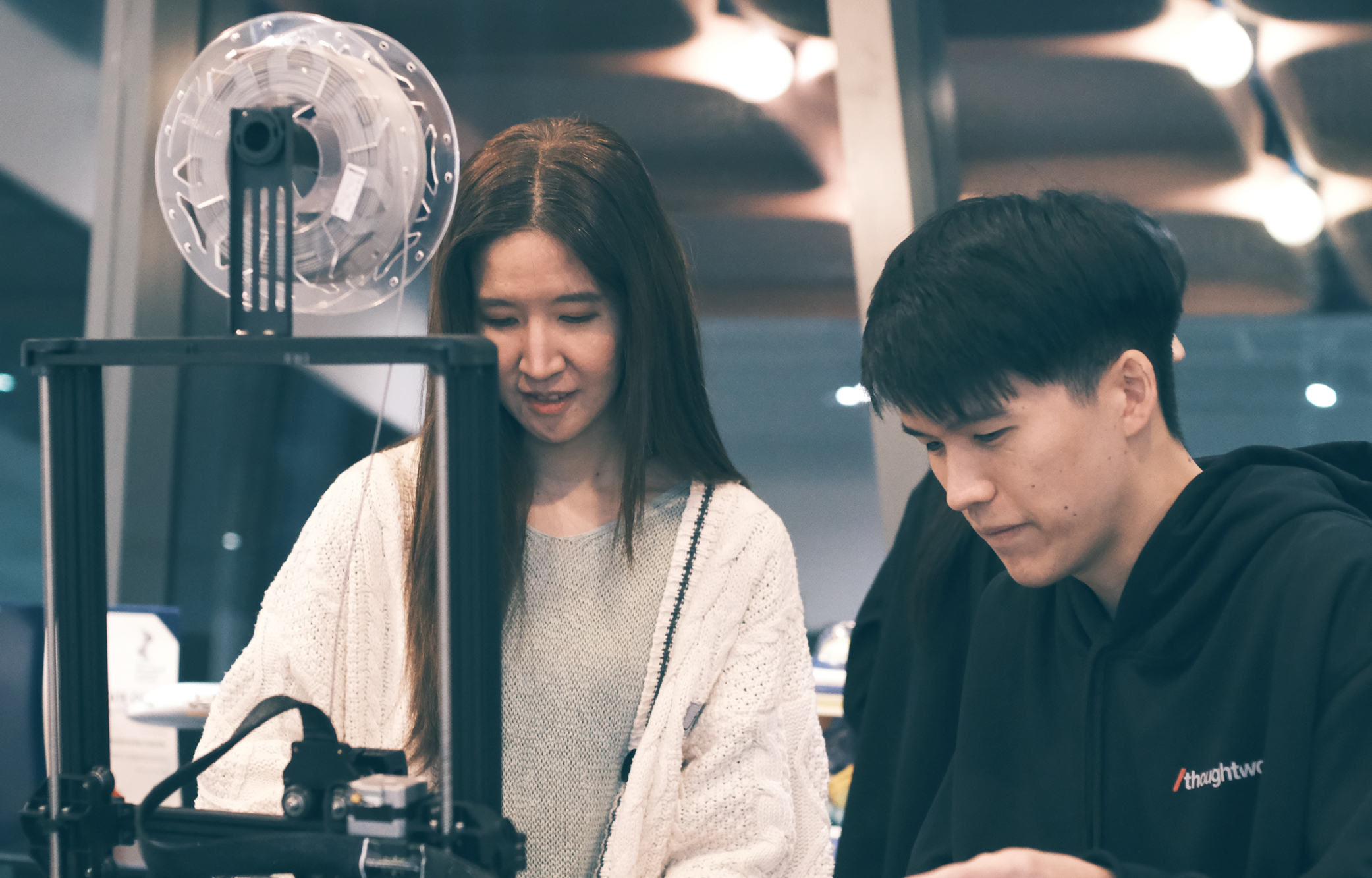 Two Thoughtworkers looking at a machine in an office.